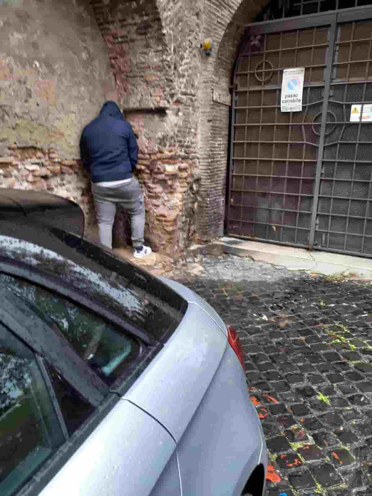 Roma pulita? Foto simbolo del buoco corso di Gualtieri sindaco: giovane la fa davanti a un portone in pieno giorno