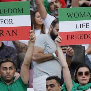 Iran, i calciatori non cantano l'inno. I tifosi li insultano. Ma dalla tribuna anche cartelli a favore dei manifestanti