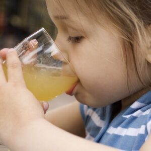 bambina beve un succo di frutta