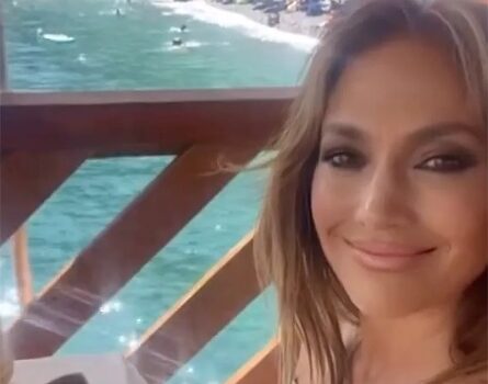 Jennifer Lopez sorridente al tavoli di un ristorante sullo sfondo di Capri