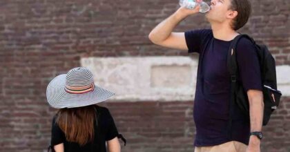 Gente che beve a causa del caldo, nel dettaglio una donna con un cappello e un uomo, senza cappello