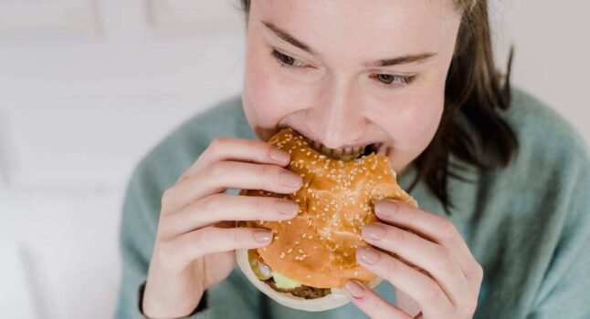 giovane donna mangia un hamburger
